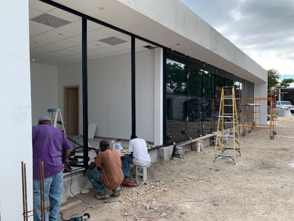 Workers installing large glass panels on a modern building.